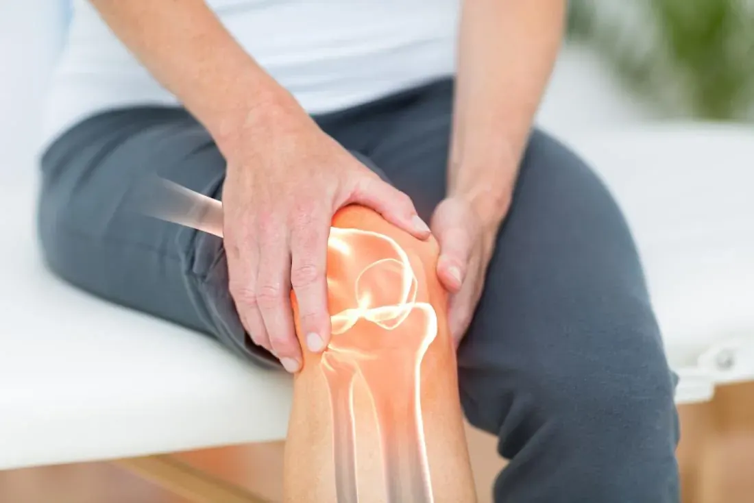 Knee joint pain — the bones of an arthritic knee highlighted while a patient holds their knee
